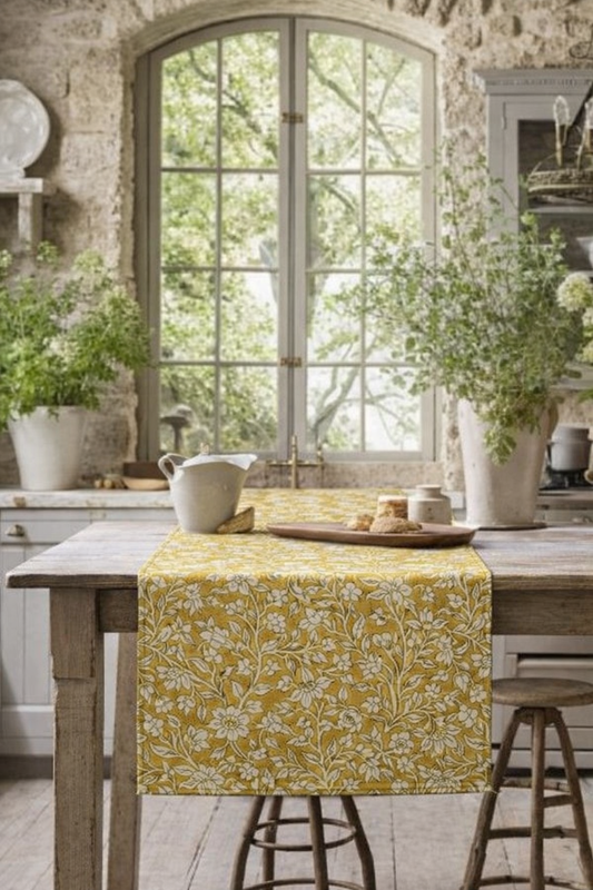 Yellow floral table runner on a wooden table with a rustic kitchen background