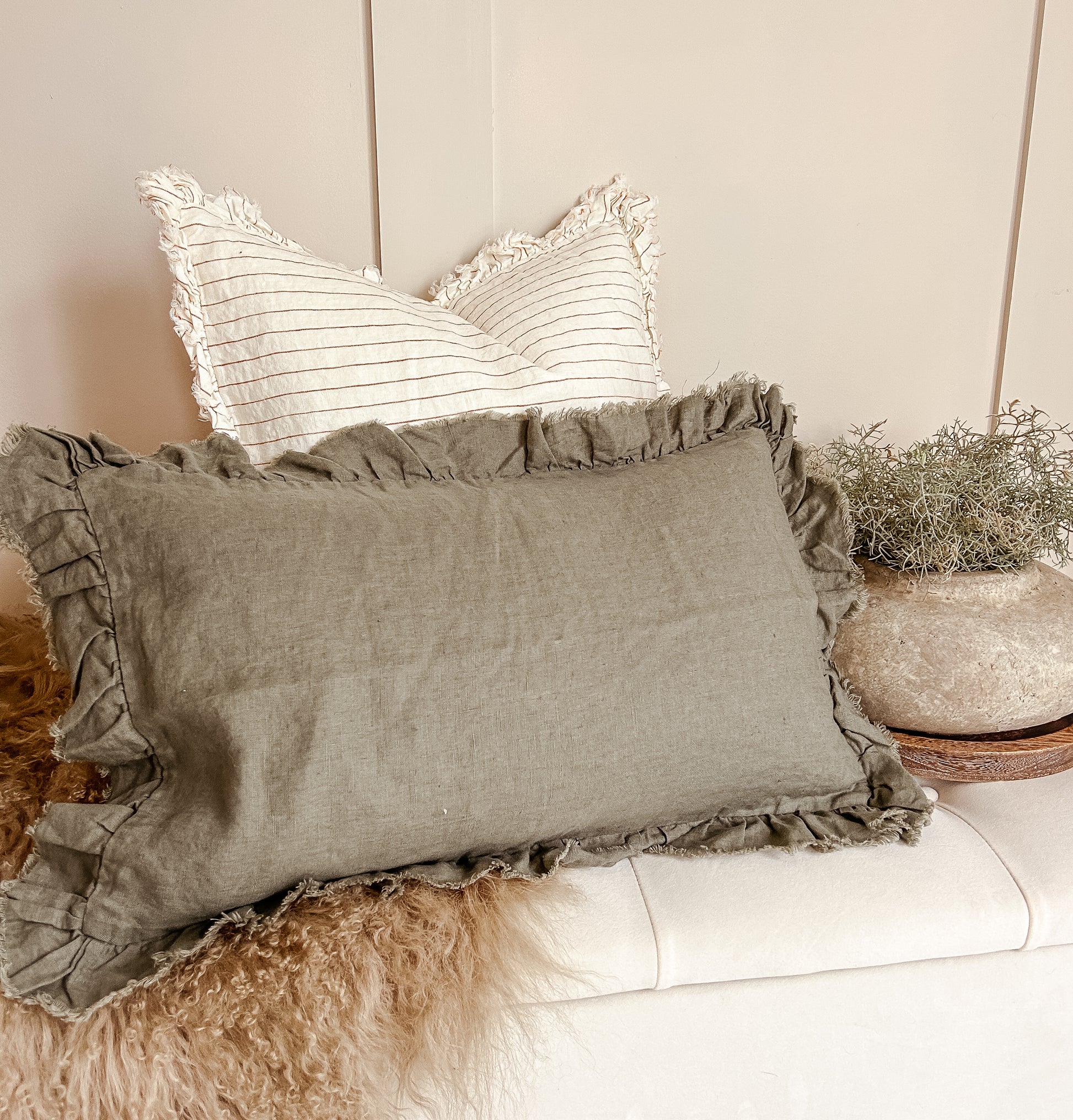 Cosy living room scene with rust ruffle cushion and ticking stripes.