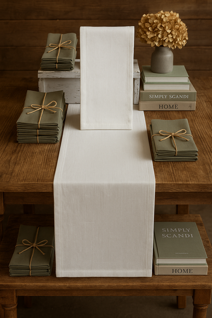 White runner on a wooden table with green books and decorative items.