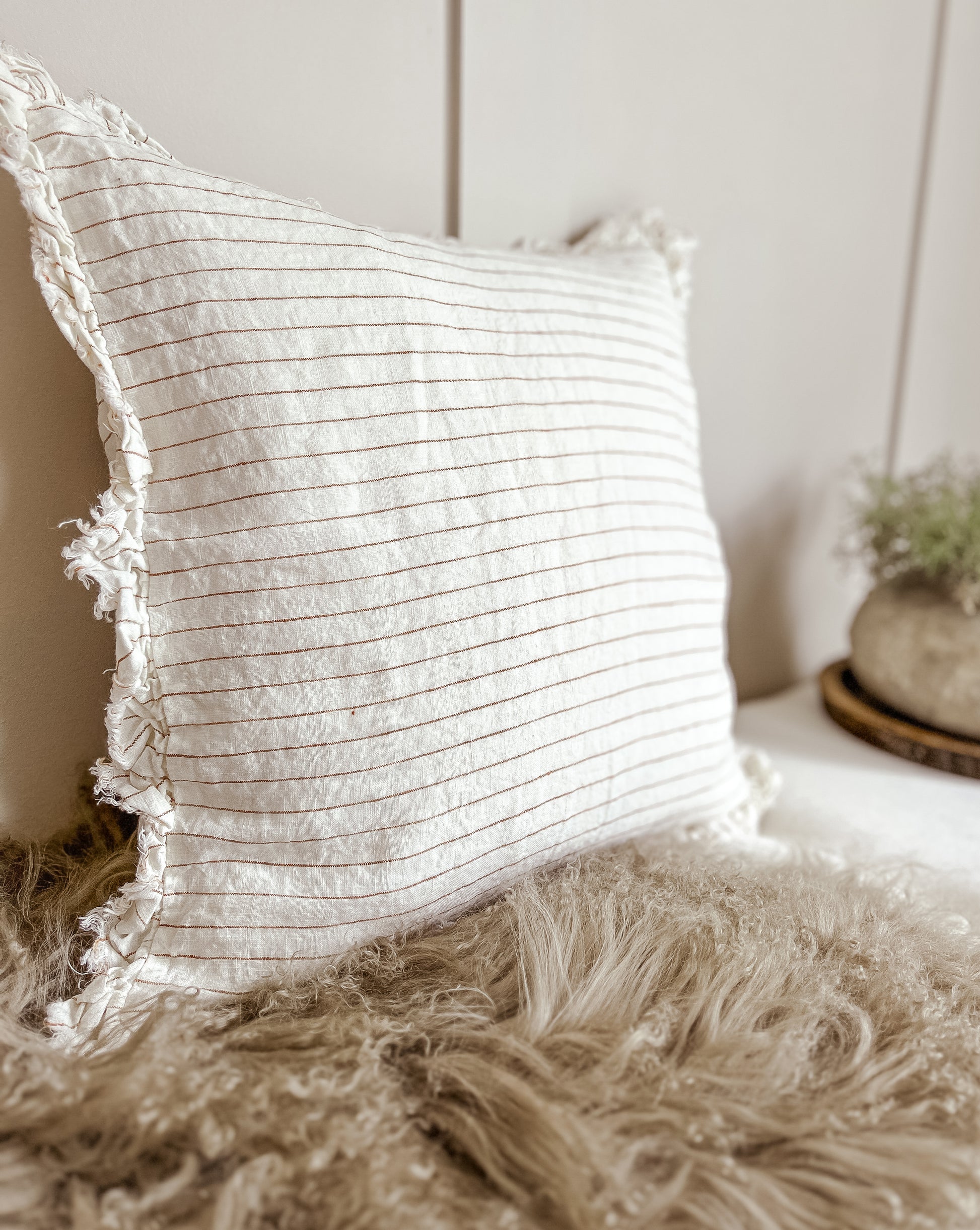 Rust striped scatter cushion, 53×53, layered with beige cushions.