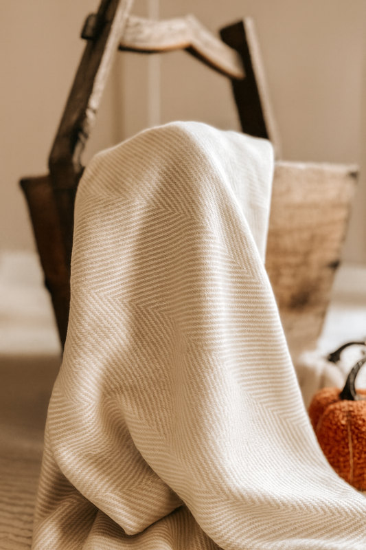 Soft neutral throw blanket in cream and beige tones with tassels—ideal for layering across the bed or sofa for extra warmth.